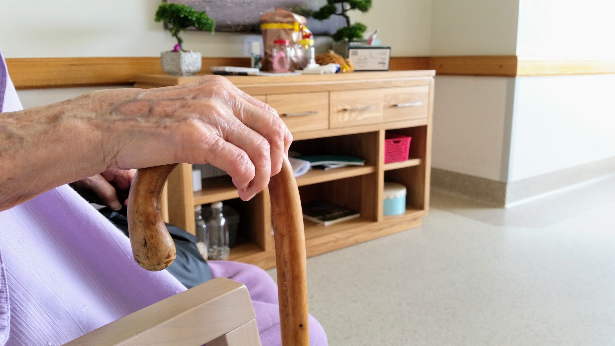 Elderly woman holding a cane while sitting down, fall prevention